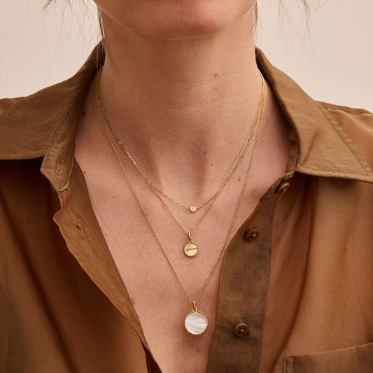 Delicate layered gold necklaces featuring a small round pendant and a larger 18-carat gold medallion with a mother-of-pearl. - Médaille Nuances nacre