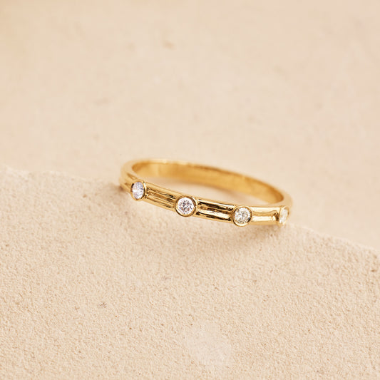 Bague fine en or jaune 18 carats sertie de diamants sur fond beige